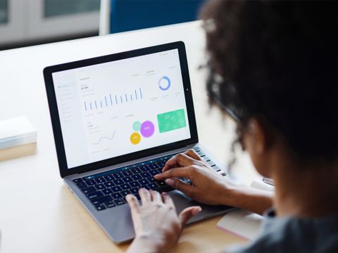 Frau arbeitet an Laptop, auf welchem Statistiken abgebildet sind