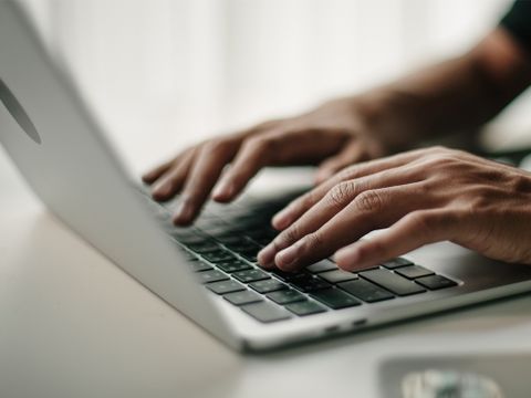 Mann tippt auf Tastatur von Laptop