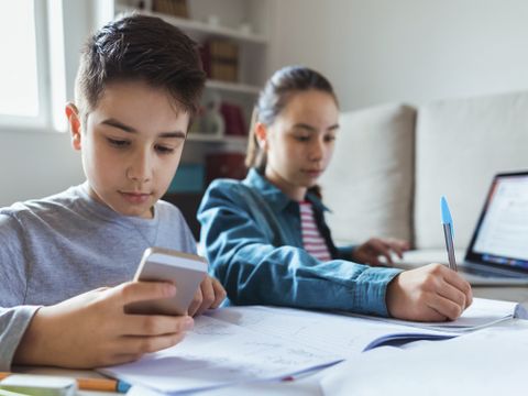 Zwei Kinder arbeiten mit Handy und Laptop