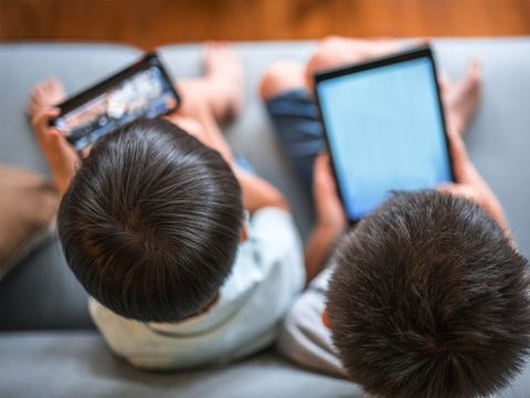 Zwei Kinder schauen auf Handy und Tablet