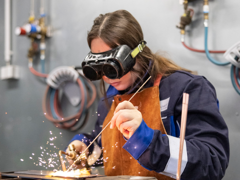 Frau schweißt mit Schutzbrille