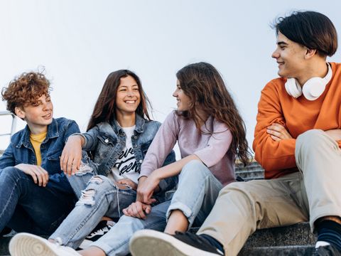 kleine Gruppe freudiger Jugendlicher unterhält sich