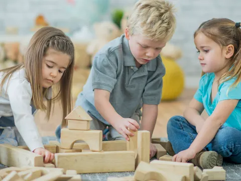 drei Kleinkinder spielen mit Holzklötzen