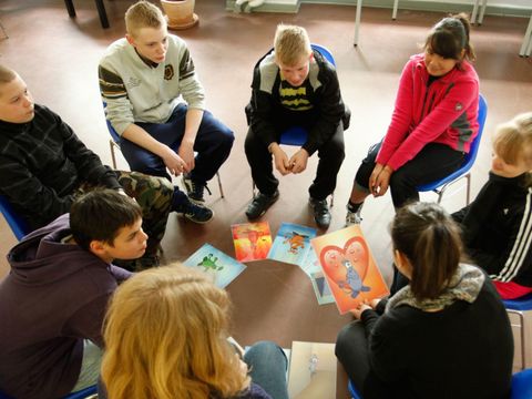 Jugendliche sitzen im Kreis und schauen Bilder an