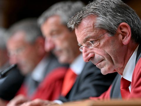 Mehrere Richter in roten Roben sitzen nebeneinander während einer Gerichtsverhandlung