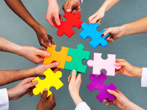 High Angle View Of Medical Team Solving Jigsaw Puzzle