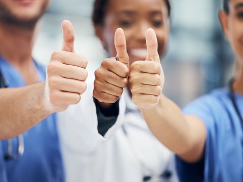 Ärzte und Krankenschwester halten drei Daumen hoch. Doctors, nurses or thumbs up hands in success, teamwork collaboration or trust with medical winner goal. Zoom on thank you, motivation and vote sign on man and support women in healthcare hospitalDoctors, nurses or thumbs up hands in success, teamwork collaboration or trust with medical winner goal. Zoom on thank you, motivation and vote sign on man and support women in healthcare hospital
