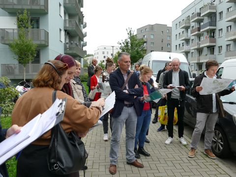 Rundgang zu EQ-Projekten in Hellersdorf - Gruppe mit Quartierskarten im Wohngebiet