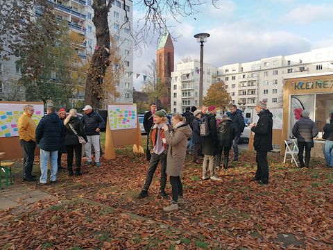 Menschen stehen in Gruppen und diskutieren auf Grünfläche