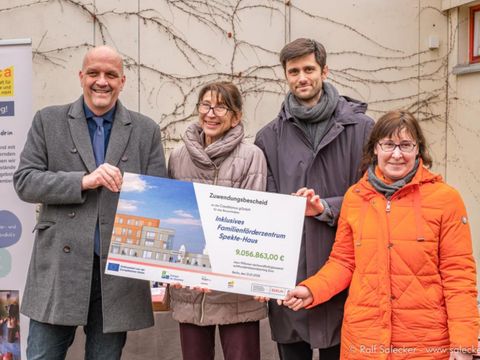 4 Personen halten einen symbolischen Scheck