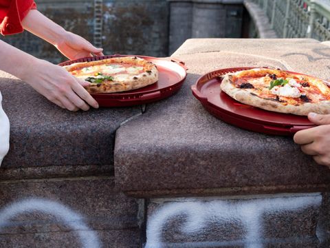 Zwei Personen essen draußen Pizza aus runden Mehrwegboxen