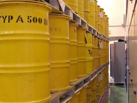 Lagerraum mit gelben Metallfässer mit Strahlenwarnzeichen in Regalen