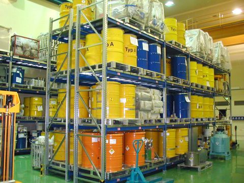 Lagerraum mit farbigen Metallfässer mit Strahlenwarnzeichen in Regalen