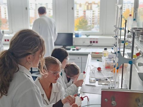 Junge Wissenschaftlerinnen in weißen Kitteln beim Experimentieren im Labor