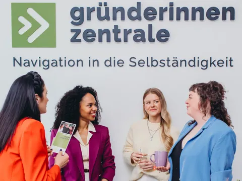 Vier Frauen reden und netzwerken vor dem Logo der Gründerinnenzentrale