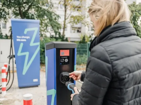 Frau bedient eine Ladesäule