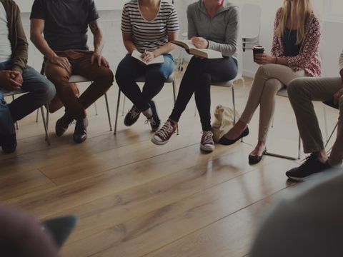 Menschen sitzen auf Stühlen in einem Kreis und diskutieren