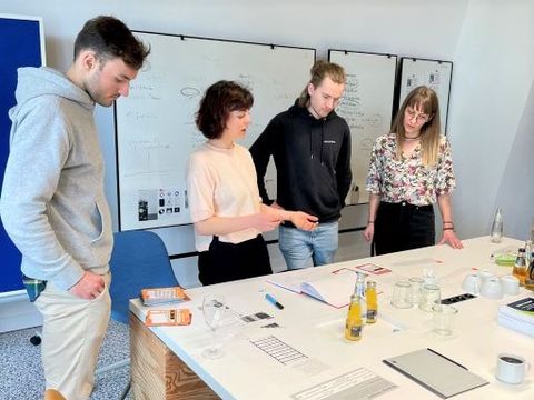 4 Menschen stehen an einem Arbeitstisch
