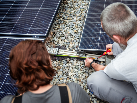Zwei Personen installieren Solarmodule.