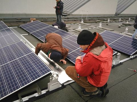 Kinder schauen sich Solarmodule auf dem Dach an