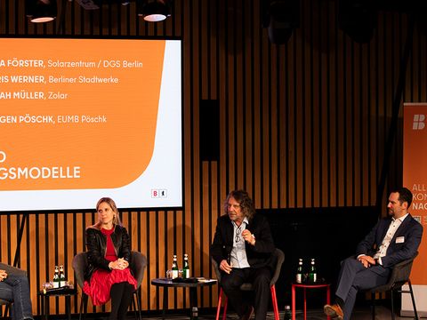 Poduimsdiskussion auf der Bühne, 4 Personen sitzen vor der Leinwand.