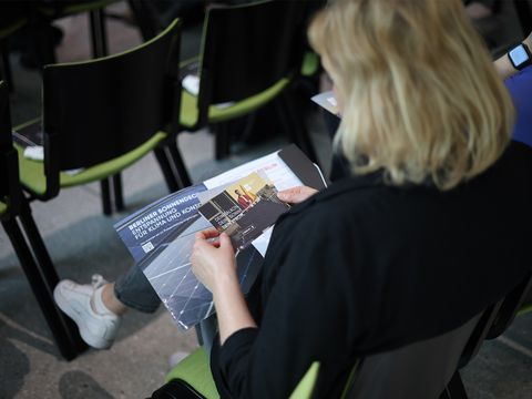 Person sitzend über die Schulter fotografiert. Sie schaut sich Solarcity Flyer an.