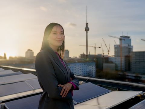 Frau auf Dach in der Mollstraße. Im Hintergrund Solarpanel und die Skyline von Berlin mit Fernsehturm.