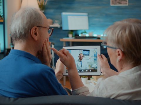 Älterer Mann und Frau im Gespräch mit dem Zahnarzt per Online-Videoanruf