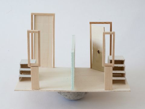 Holzkonstruktion, die etwas von einem Architekturmodells eines Raumes hat, der auf einem wackeligen Boden steht