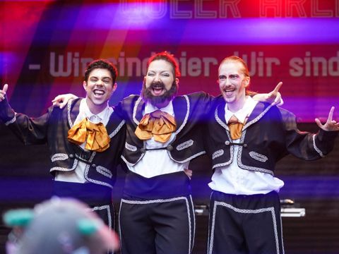 Drei Drag Kings stehen auf einer Bühne