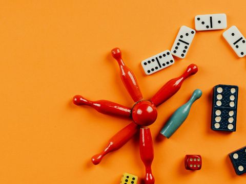 Würfel und Spielfugren vor gelbem Hintergrund