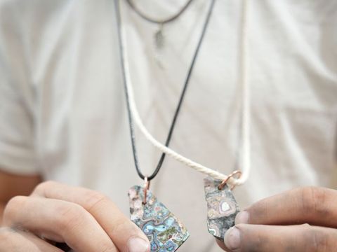 Person halt bunte Kettenanhänger in die Kamera