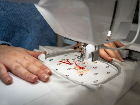 Hand und Stoff mit Stickerei an Stickmaschine