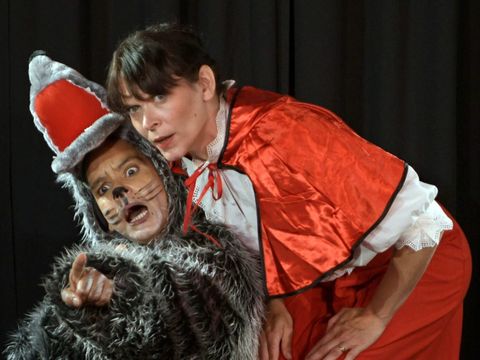 zwei Personen in Kostümen von Rotkappchen und dem Wolf