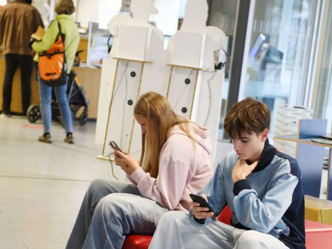 Zwei Jugendliche schauen im Foyer der Bibliothek auf ihre Handys