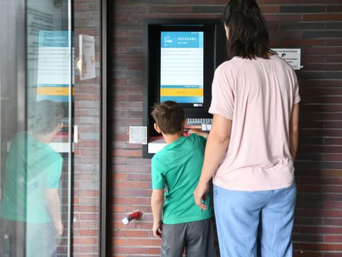Eine Mutter leiht mit ihren Sohn etwas in der Hansabibliothek am Automaten aus