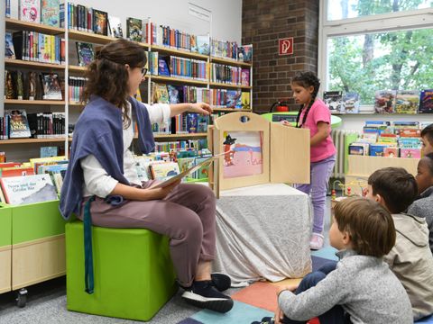 Eine Bibliothekarin liest einer Kindergruppe vor