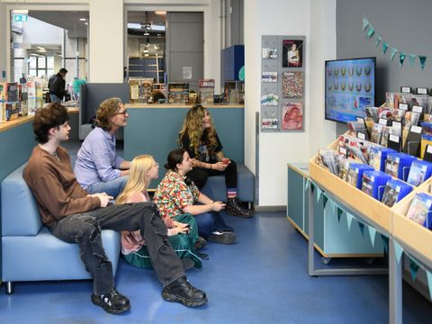 Menschen spielen im Gamingbereich de Philipp-Schaeffer-Bibliothek zusammen ein Spiel an der Playstation 5