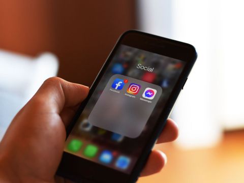 Eine Hand hält ein Smartphone in der Hand, auf dem Icons von sozialen Medien sichtbar sind