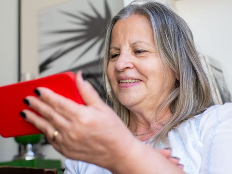 Eine ältere Frau schaut sich auf ihrem Smartphone etwas an