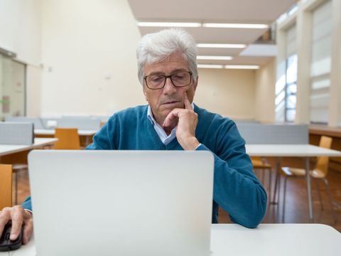 Ein älterer Mann sitzt am Laptop und arbeitet