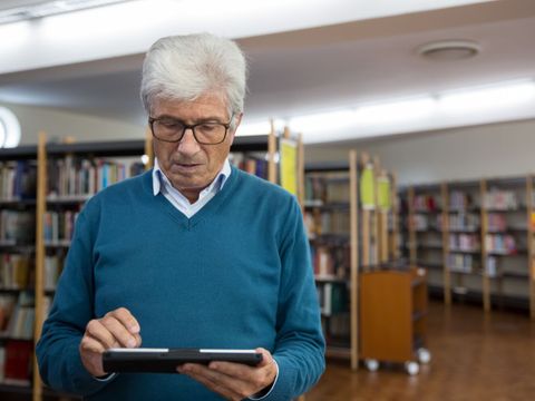 Eine älterer Mann schaut sich auf einem Tablet etwas an