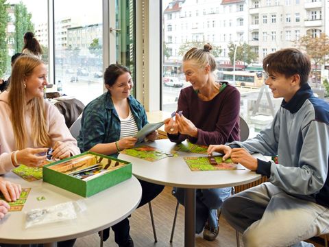 Vier Menschen spielen zusammen in der Schiller-Bibliothek ein Gesellschaftsspiel