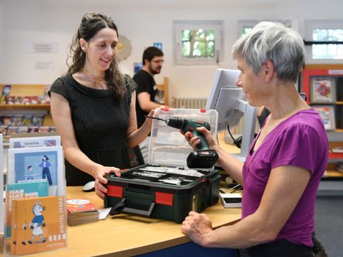 Eine Frau leiht einen Werkzeugkoffer aus