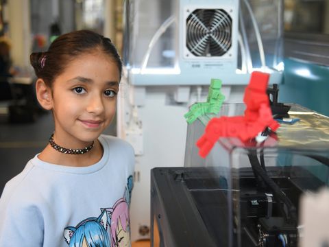 Ein Kind steht neben einem Gerät im Makerspace