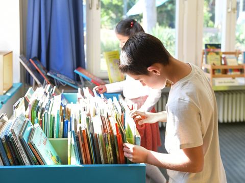 Ein Junge sieht sich die Bücher in einer Kiste an