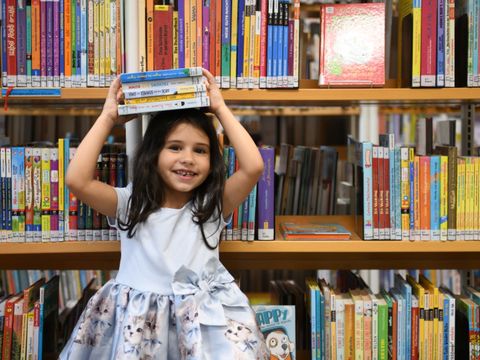 Ein Kind hält sich Bücher über den Kopf