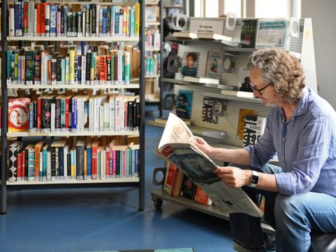 Ein Mann liest in einer Bibliothek Zeitung