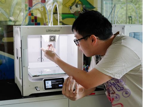 ein Jugendlicher guckt in einen 3D-Drucker nach dem Filamentfaden