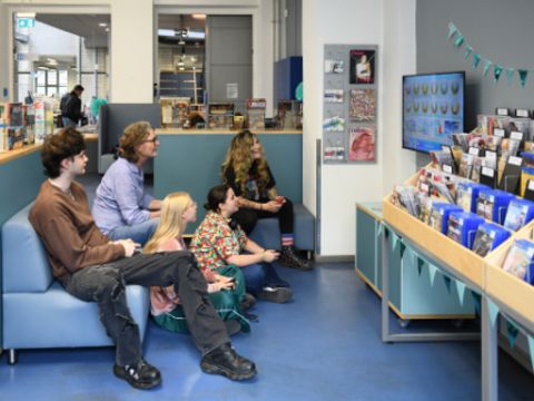 Mehrere Personen sitzen vor einem großen Bildschirm